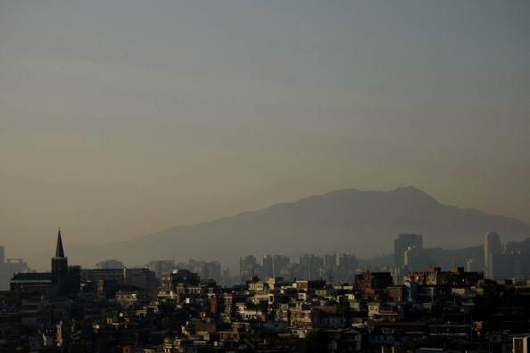 Morning sunlight illuminates residential properties north of the Han River, backdropped by mountains and skyscrapers in the Gangnam business district