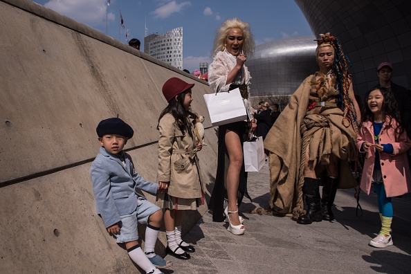 Children pose with spectators waiting to see a fashion show outside the Dongdaemun Design Plaza in Seoul on Wednesday.