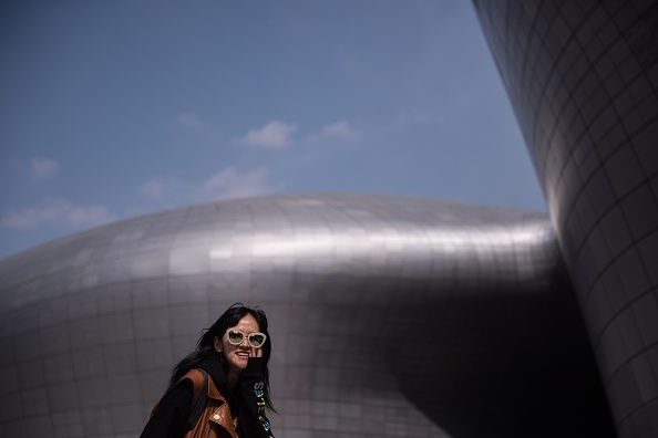 A fashion fan stands against the futuristic backdrop of the Dongdaemun Design Plaza.