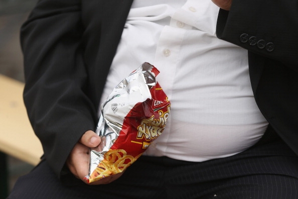 heavyweight man eating junkfood, which is high in calories and one of the foods that could lead to obesity when taken in huge amounts