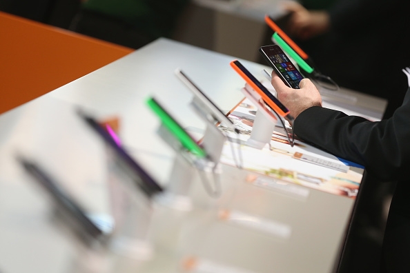 Visitors look at Windows-enabled smartphones, including the Nokia Lumia series, at the Microsoft stand the 2015 CeBIT technology trade fair in Hanover, Germany.